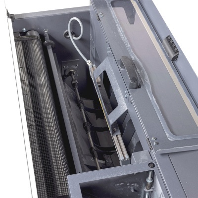 Máquina industrial cinzenta com painel aberto mostrando cilindro metálico texturizado e componentes internos