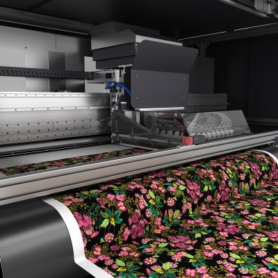 Impressora industrial a imprimir tecido floral colorido sobre fundo preto
