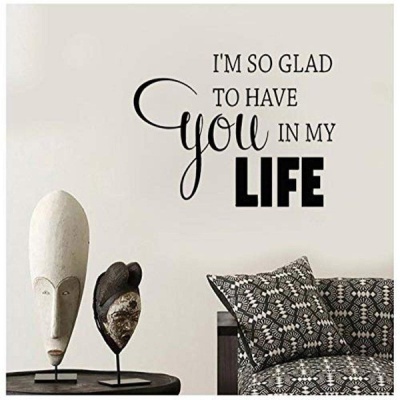 Decoração de parede com máscaras tribais e texto inspirador ao lado de sofá com almofadas geométricas preto e branco.