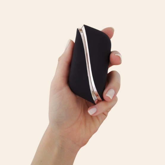Satisfyer Traveler | Sugador com capa para viagem Bolsa pequena preta com detalhe metálico prateado na mão