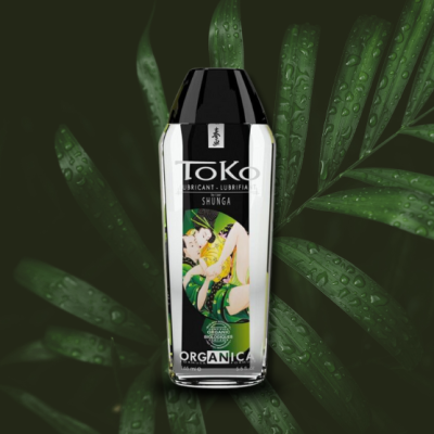 Frasco de lubrificante Shunga Toko com rótulo ilustrado e folhas verdes ao fundo