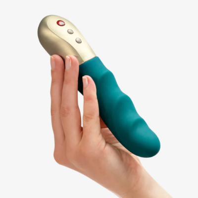 Vibrador azul esverdeado com botões dourados segurado por uma mão