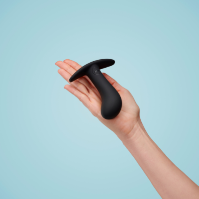 Dispositivo anatómico preto em mão sobre fundo azul claro