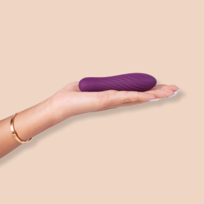 Mão a segurar vibrador pequeno roxo com textura ondulada