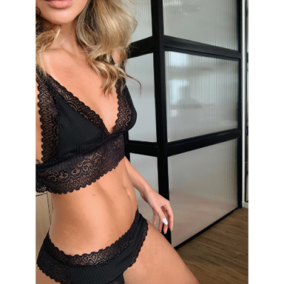Conjunto de lingerie preto em renda usado por mulher em ambiente interior