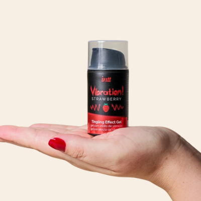 Gel Vibrating Strawberry em frasco preto com tampa transparente na mão