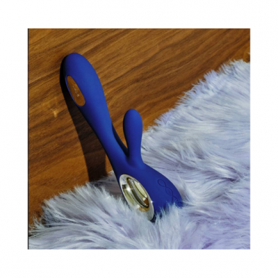 Vibrador azul de silicone com detalhes dourados em superfície de madeira e tecido felpudo