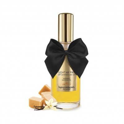 Frasco de óleo corporal com tampa dourada e laço preto, caramelo e flor branca