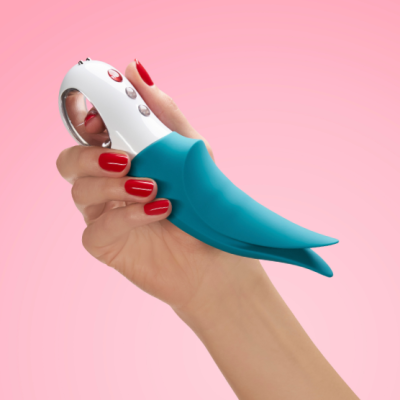 máquina de massagem azul-turquesa e branca em mão com unhas vermelhas num fundo rosa