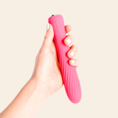 Mão segurando vibrador rosa em silicone com botões de controlo e textura ondulada