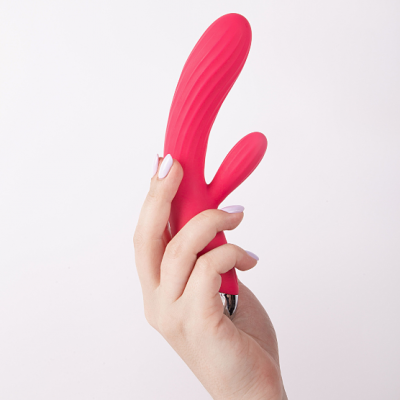 Vibrador vermelho em silicone com textura ondulada na mão