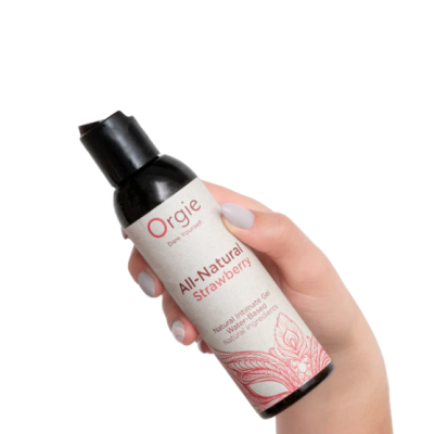 Frasco preto com gel íntimo natural sabor morango e rótulo branco e rosa na mão