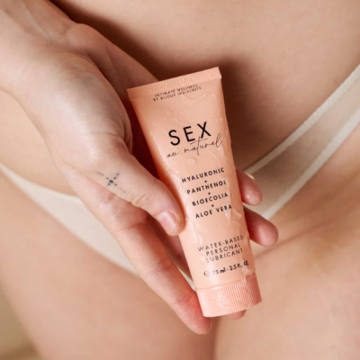 Frasco cor de pêssego de lubrificante pessoal à base de água segurado por uma mão