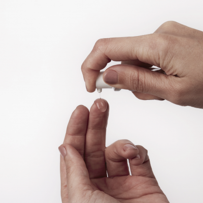 Mãos aplicando líquido transparente no dedo com aplicador branco