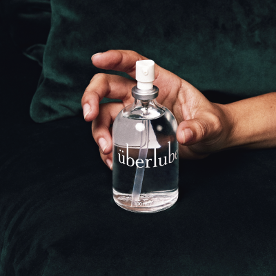 Frasco com pulverizador de lubrificante claro sobre fundo verde escuro