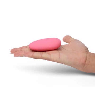 Objeto oval cor de rosa em mão de pessoa sobre fundo branco.