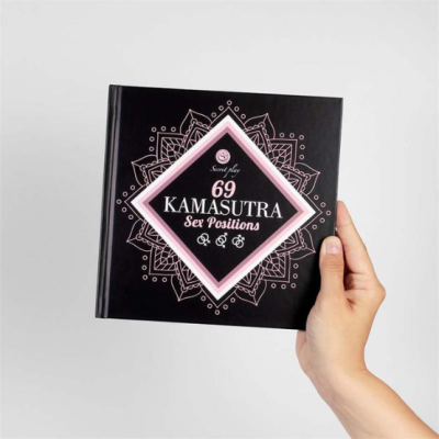 Livro preto '69 KAMASUTRA Sex Positions' com texto rosa e branco segurado por uma mão