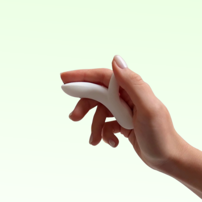 Mão segurando objeto branco curvado com fundo verde claro