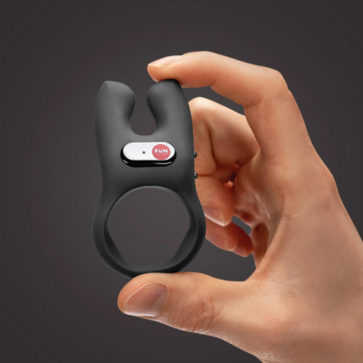 Anel vibratório preto com placa metálica e texto FUN