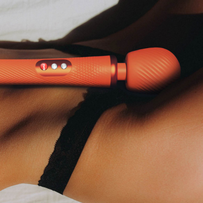 Vibrador massajador laranja com botões e textura sobre pele com lingerie preta