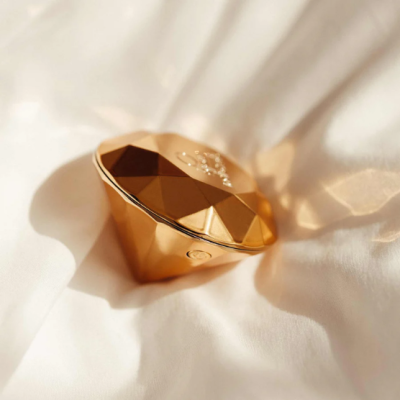 Caixa dourada em forma de diamante sobre tecido branco