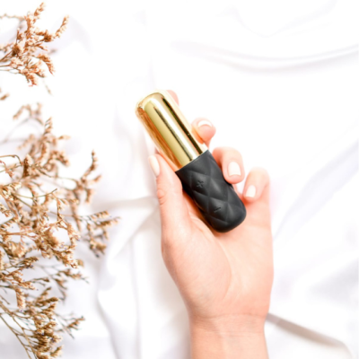 Frasco de batom preto com tampa dourada na mão de uma pessoa