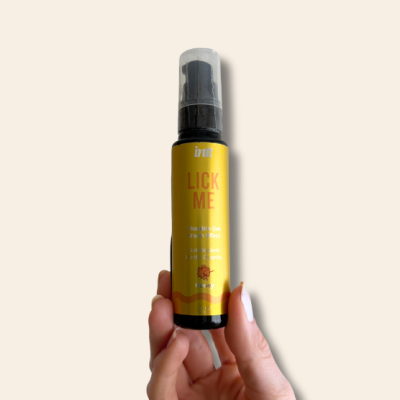 Frasco amarelo de gel beijável Lick Me com doseador preto, segurado por mão