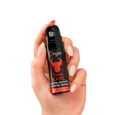 Frasco preto de creme corporal com texto vermelho e branco segurado por mão feminina