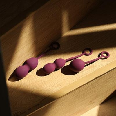 Três bolas de silicone roxas com argolas, sobre escadaria de madeira