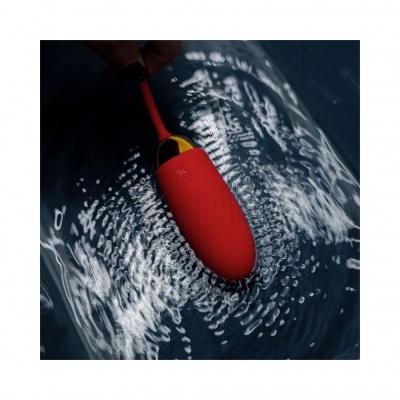 Dispositivo vermelho com cabo vermelho e parte metálica dourada na água