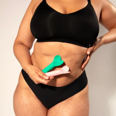 Mulher com biquíni preto segurando objetos anatómicos verdes e rosas