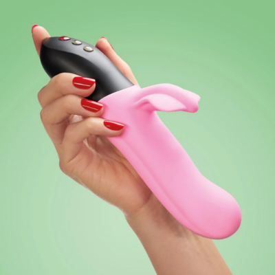 Mão a segurar vibrador rosa com controlo preto