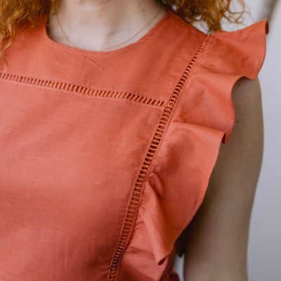 Close-up de vestido laranja com detalhes em renda e babados na manga