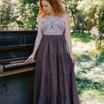 Vestido longo castanho com parte superior branca de linhas cruzadas ao ar livre junto a piano antigo