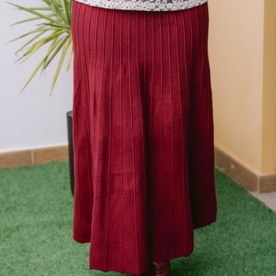 Saia vermelha longa canelada com botas vermelhas e blusa branca de crochê.