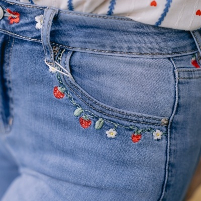 Jeans azul claro com bordado de morangos e flores no bolso e camisa branca com corações vermelhos