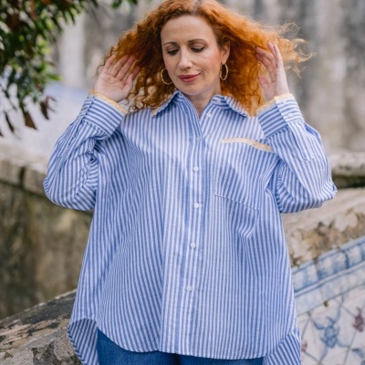 Camisa riscas azuis e brancas com calças de ganga azuis em ambiente exterior