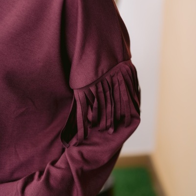 Detalhe de sweatshirt bordeaux com franjas no ombro
