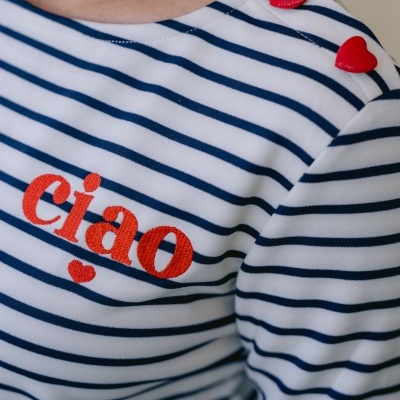 Camisola branca com riscas azuis e botões vermelhos em forma de coração no ombro