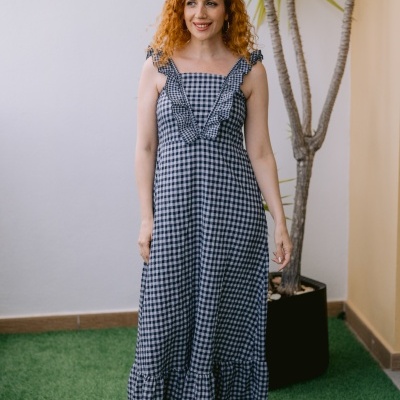 Vestido azul e branco xadrez com folhos e mulher ruiva numa varanda com planta.