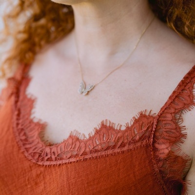 Vestido terra com renda na gola e alças, colar com pendente de borboleta.