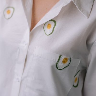 Camisa branca com padrão bordado de ovos amarelos e verdes em tecido liso