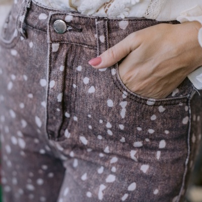 Calças de ganga castanhas com manchas brancas e blusa branca rendada