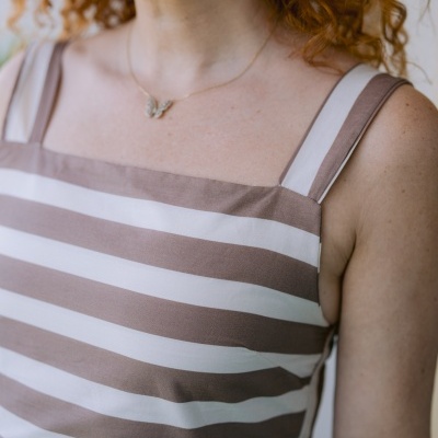 T-shirt de alças largas com riscas bege e branco e colar de borboleta.