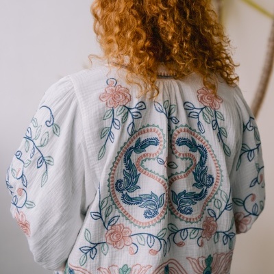 Blusa bordada branca com padrões florais coloridos vista de costas