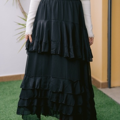 Saia preta comprida com folhos em camadas, botas vermelhas e blusa branca com renda