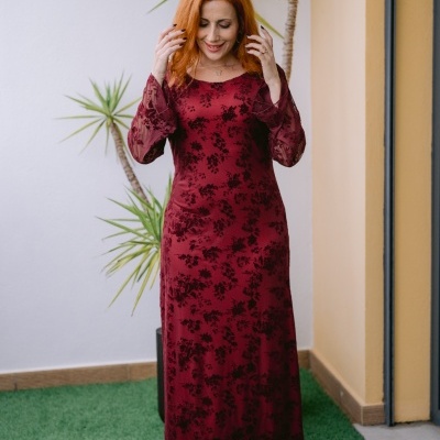 Vestido comprido vermelho vinho com padrão floral preto e mangas transparentes.