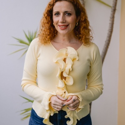 Camisola amarela clara com folhos ondulados, mangas compridas, usada por mulher com calças de ganga azul