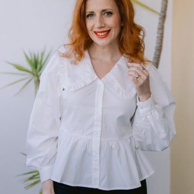 Blusa branca com gola ampla e mangas bufantes usada por mulher