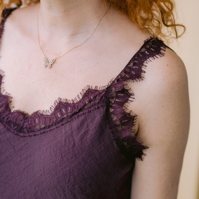 Top feminino roxo com renda na borda e colar dourado em forma de asas